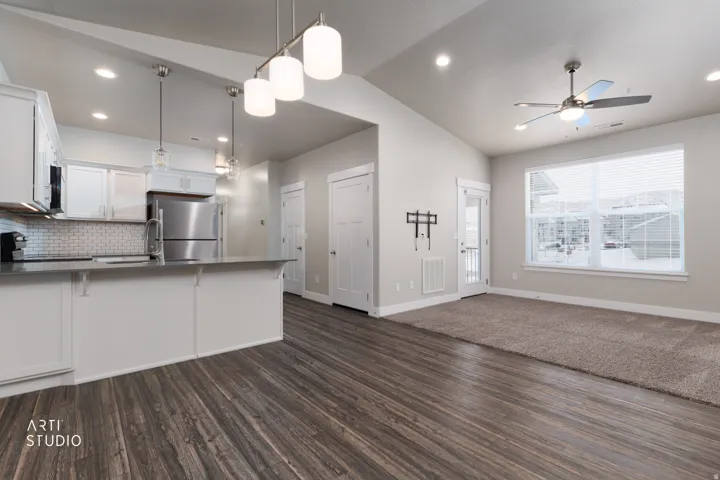 Kitchen with white cabinets, a peninsula, open floor plan, vaulted ceiling, and black appliances