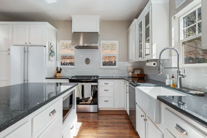 Kitchen featuring stainless steel appliances, white cabinetry, and dark stone counters