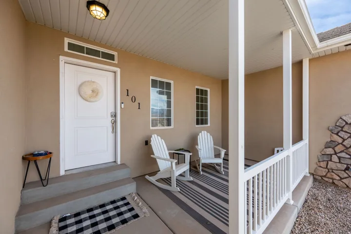 Entrance to property featuring covered porch and stucco siding
