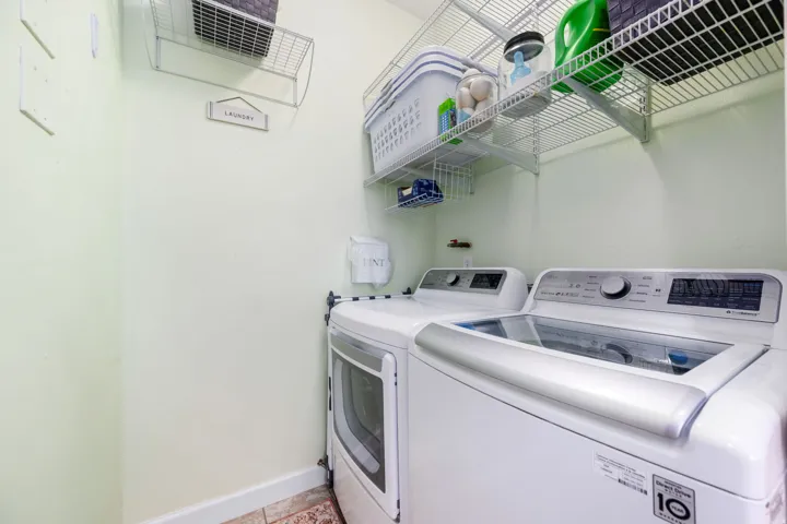 Laundry room with washer and clothes dryer and light tile patterned floors
