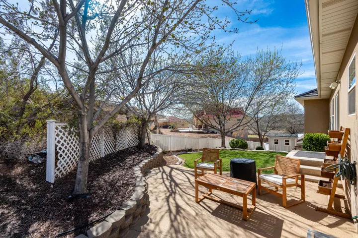 Expansive outdoor patio featuring concrete paving, a tiered retaining wall, and a white lattice fence