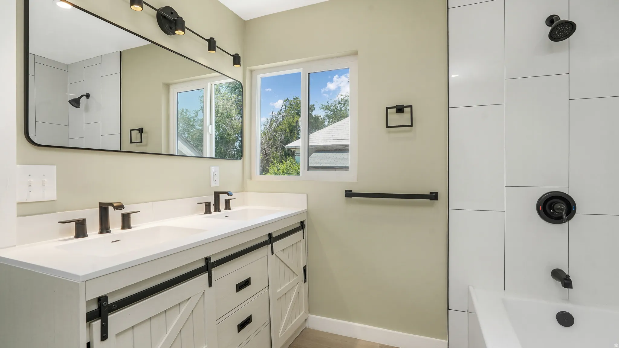 Full bathroom with double vanity and shower / washtub combination