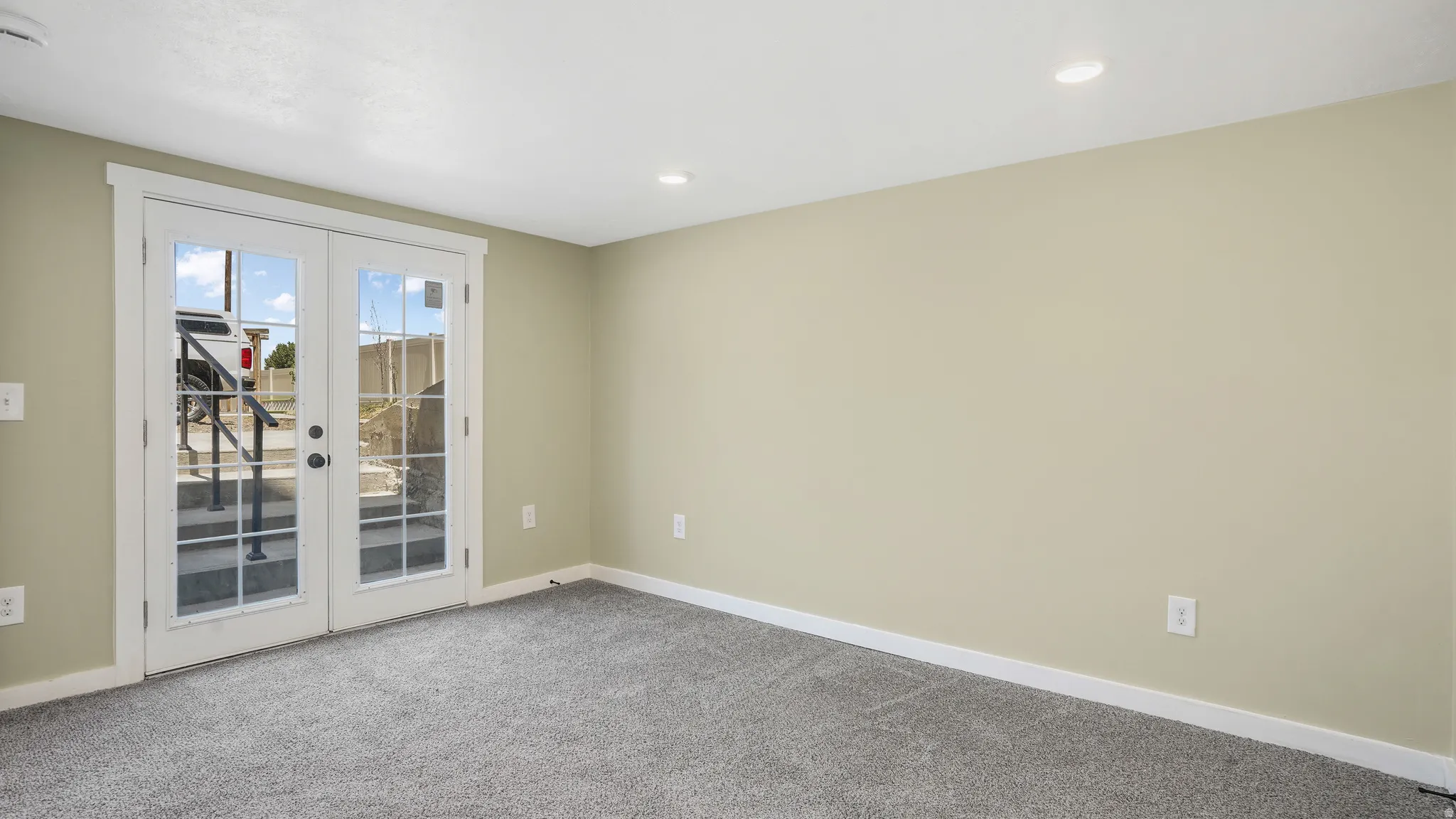 Empty room with french doors, light colored carpet, and recessed lighting