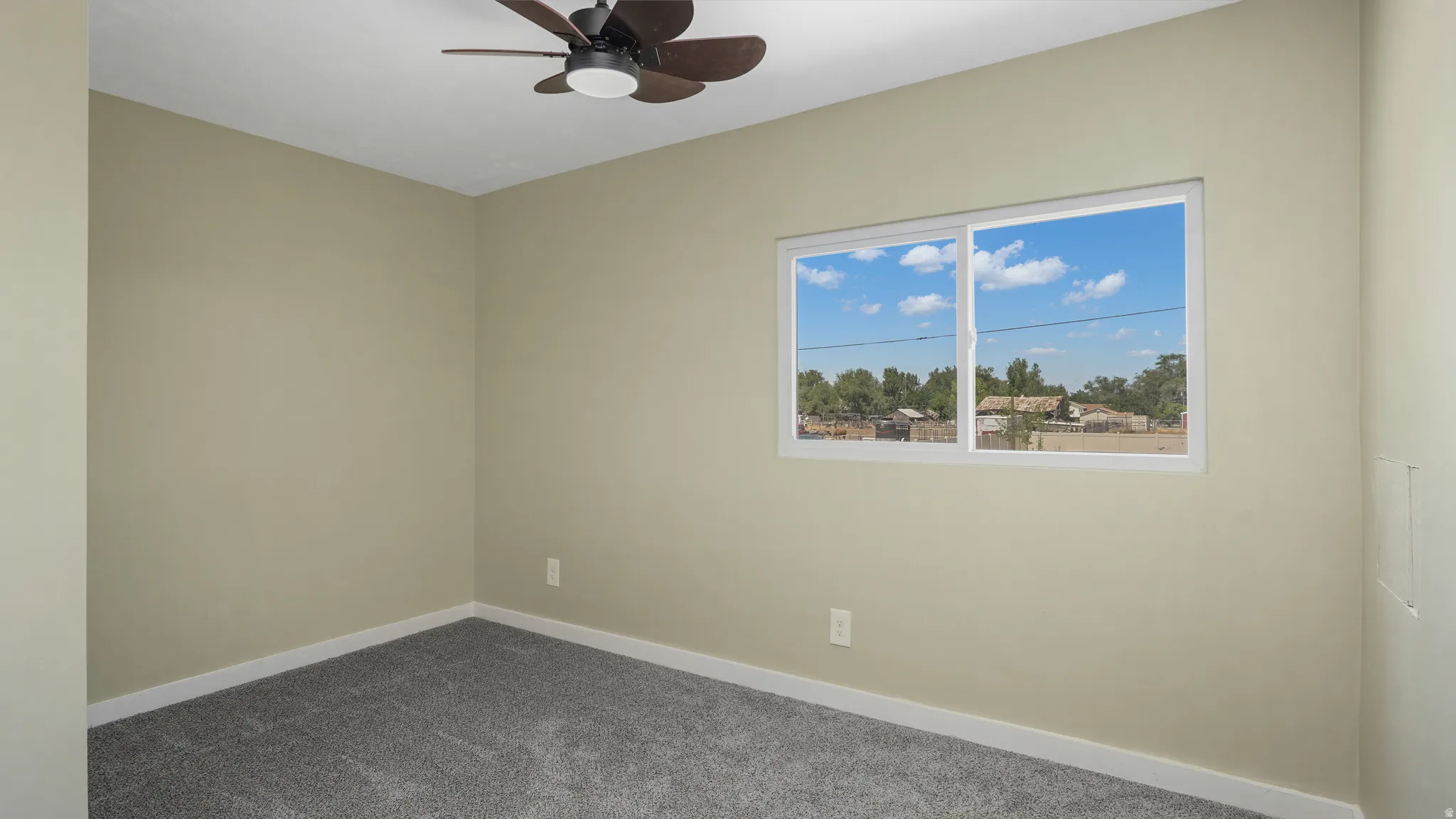 Carpeted spare room featuring baseboards and ceiling fan