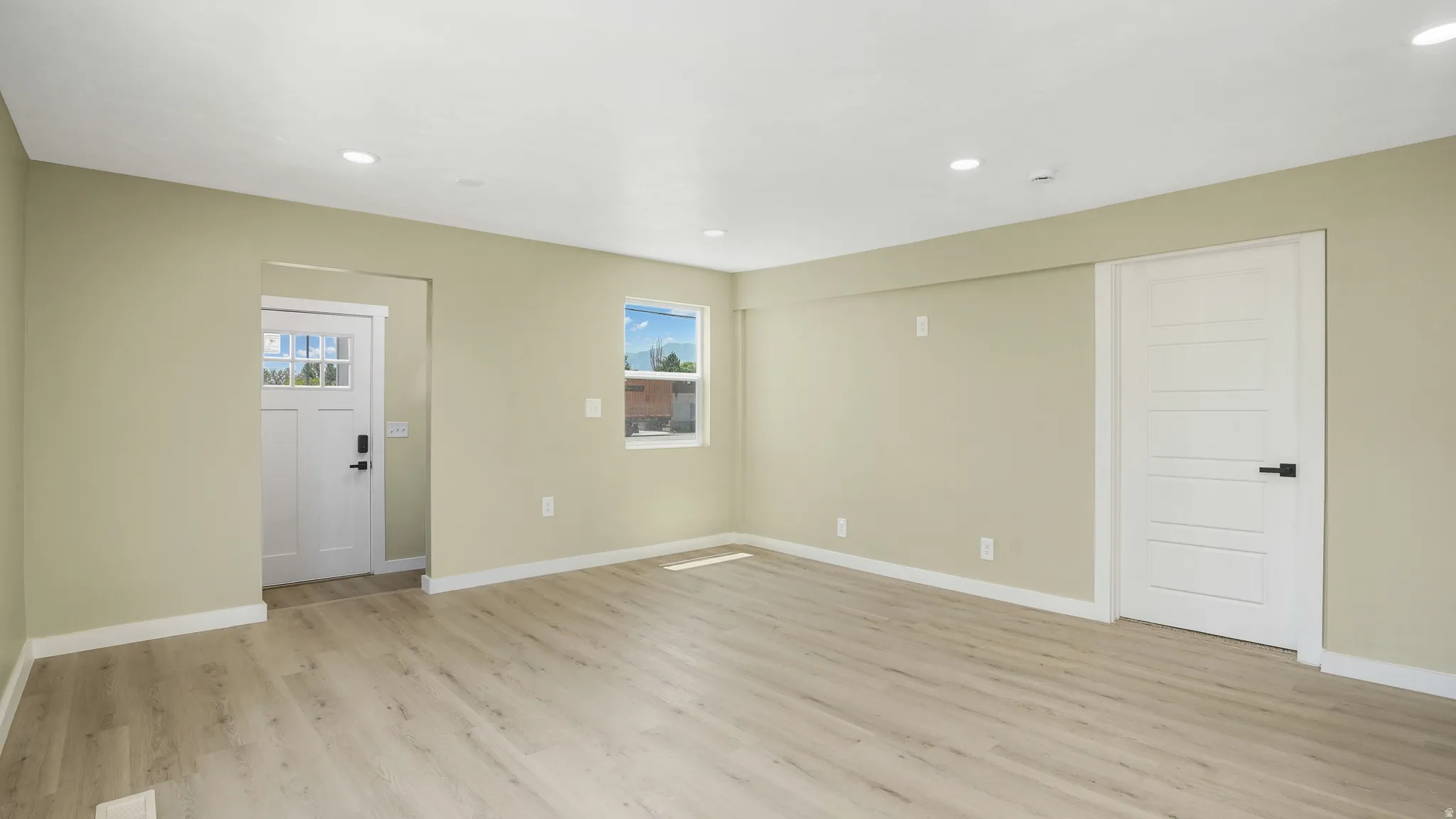Empty room with light wood-style floors and recessed lighting