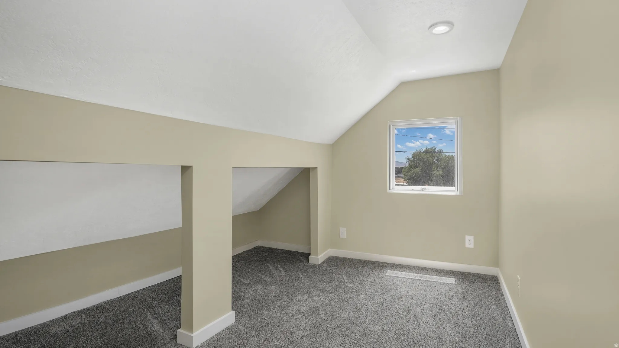 Bonus room with vaulted ceiling and carpet