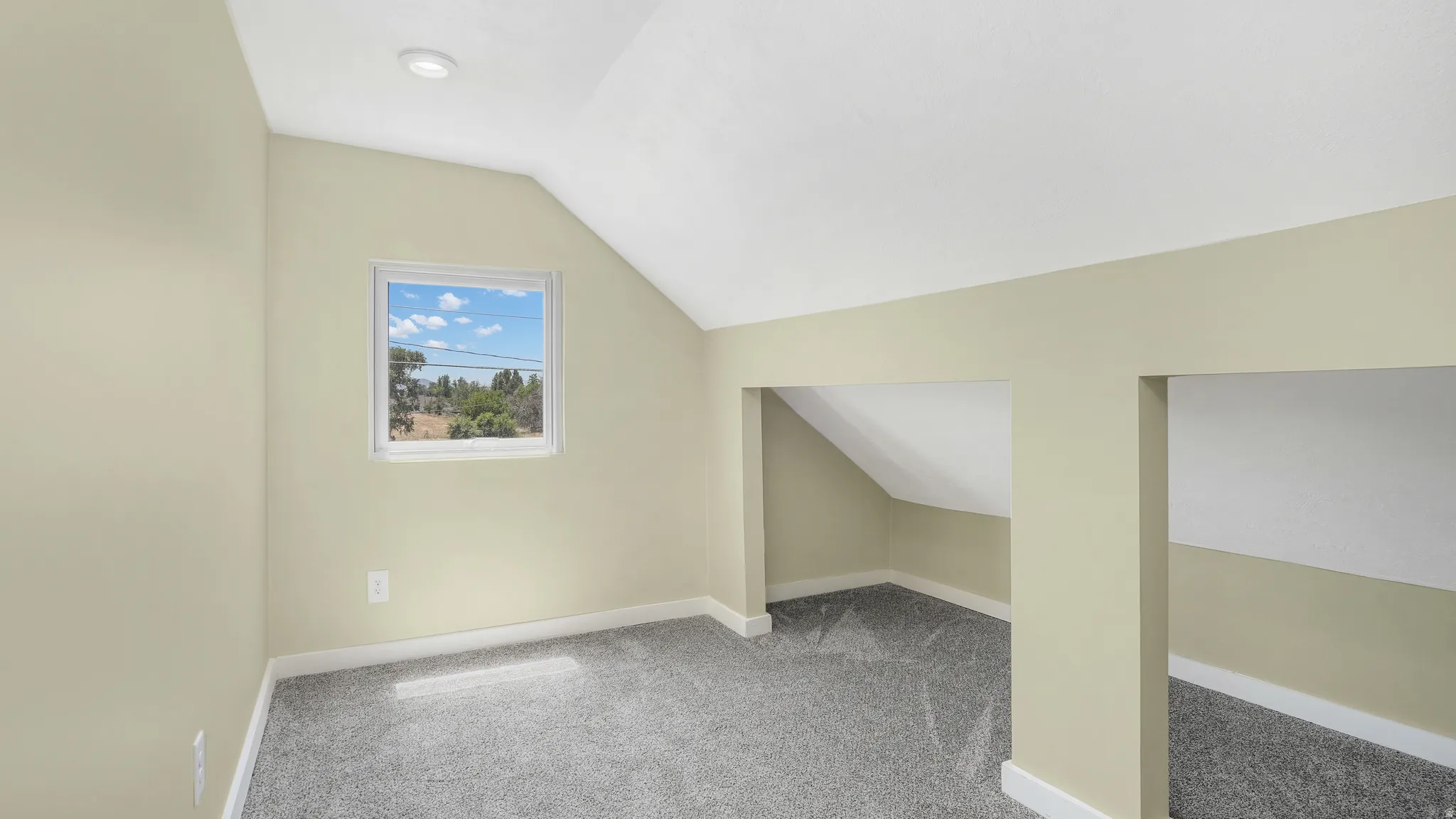 Additional living space with vaulted ceiling and light carpet