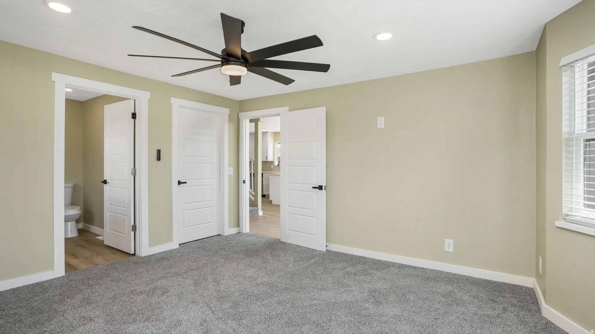Unfurnished bedroom with carpet floors, a ceiling fan, connected bathroom, and recessed lighting