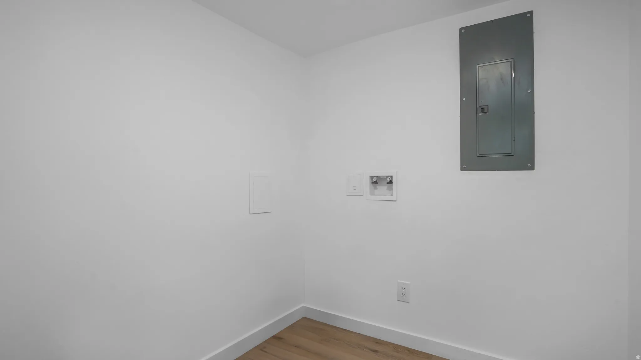 Empty room with electric panel and light wood-style floors