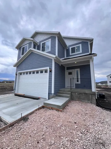 View of front facade featuring covered porch, concrete driveway, and a garage