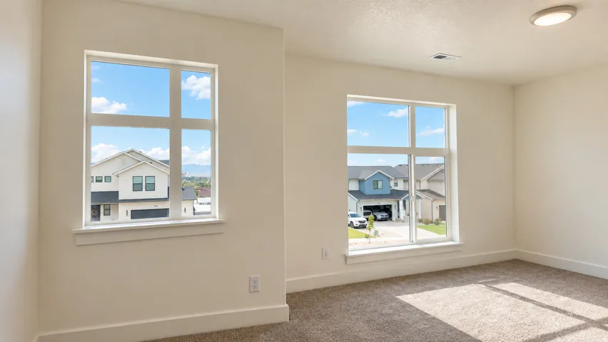 Two large windows with white trim, neutral carpet, light-colored walls, and a ceiling-mounted light fixture