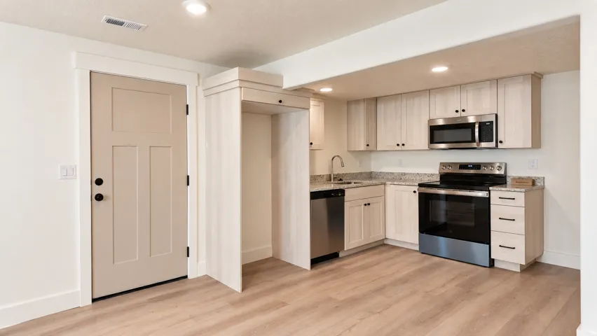 Wood-finish flooring throughout, recessed lighting, light-toned cabinetry, stainless steel appliances, and light-toned countertops