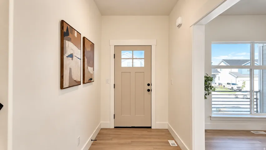 Entryway featuring a paneled door with windowpanes, wood-finish flooring, and crisp white trim