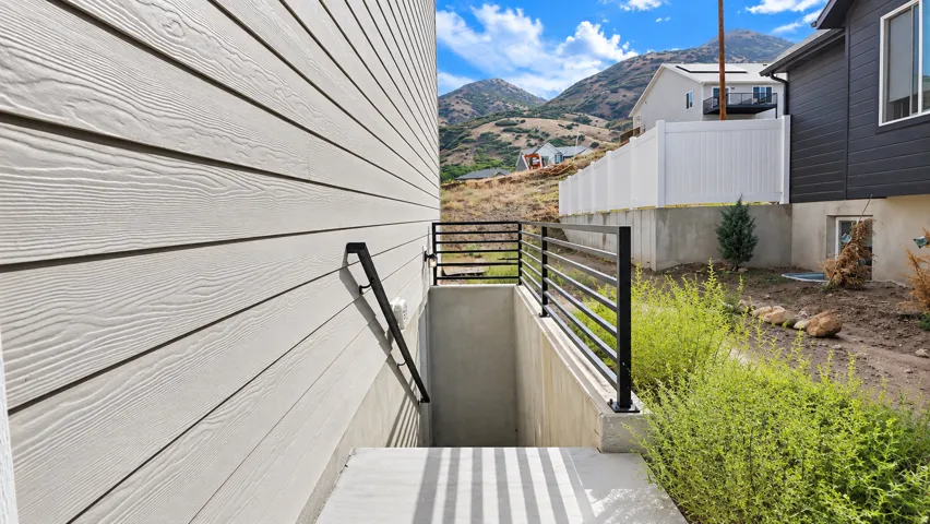 Exterior featuring light-colored siding, a concrete staircase, and black metal railings