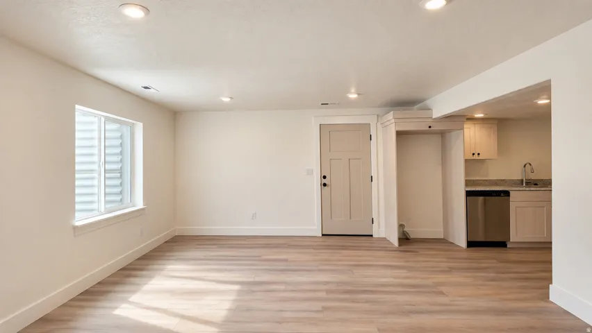 Recessed lighting, wood-finish flooring, light-toned walls, and a window with a white frame