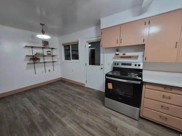 Kitchen featuring open shelves, stainless steel electric range, light countertops, dark wood-style flooring, and hanging light fixtures