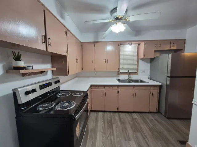 Kitchen with electric range, freestanding refrigerator, light countertops, a ceiling fan, and light wood-style floors