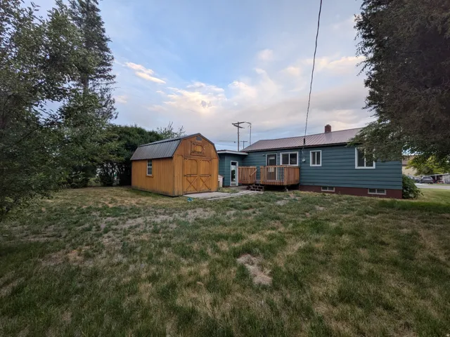 Rear exterior featuring a metal roof, teal siding, and a wood deck