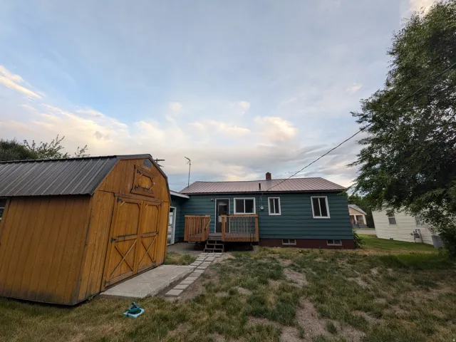 Rear exterior featuring teal siding, a brown metal roof, and a wood deck