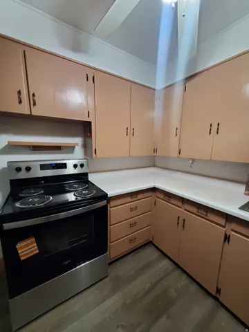 Kitchen featuring electric stove, light countertops, and dark wood-type flooring