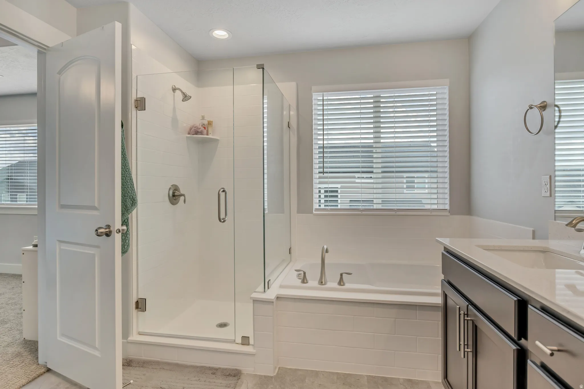 Bathroom featuring vanity, a garden tub, a shower stall, and recessed lighting