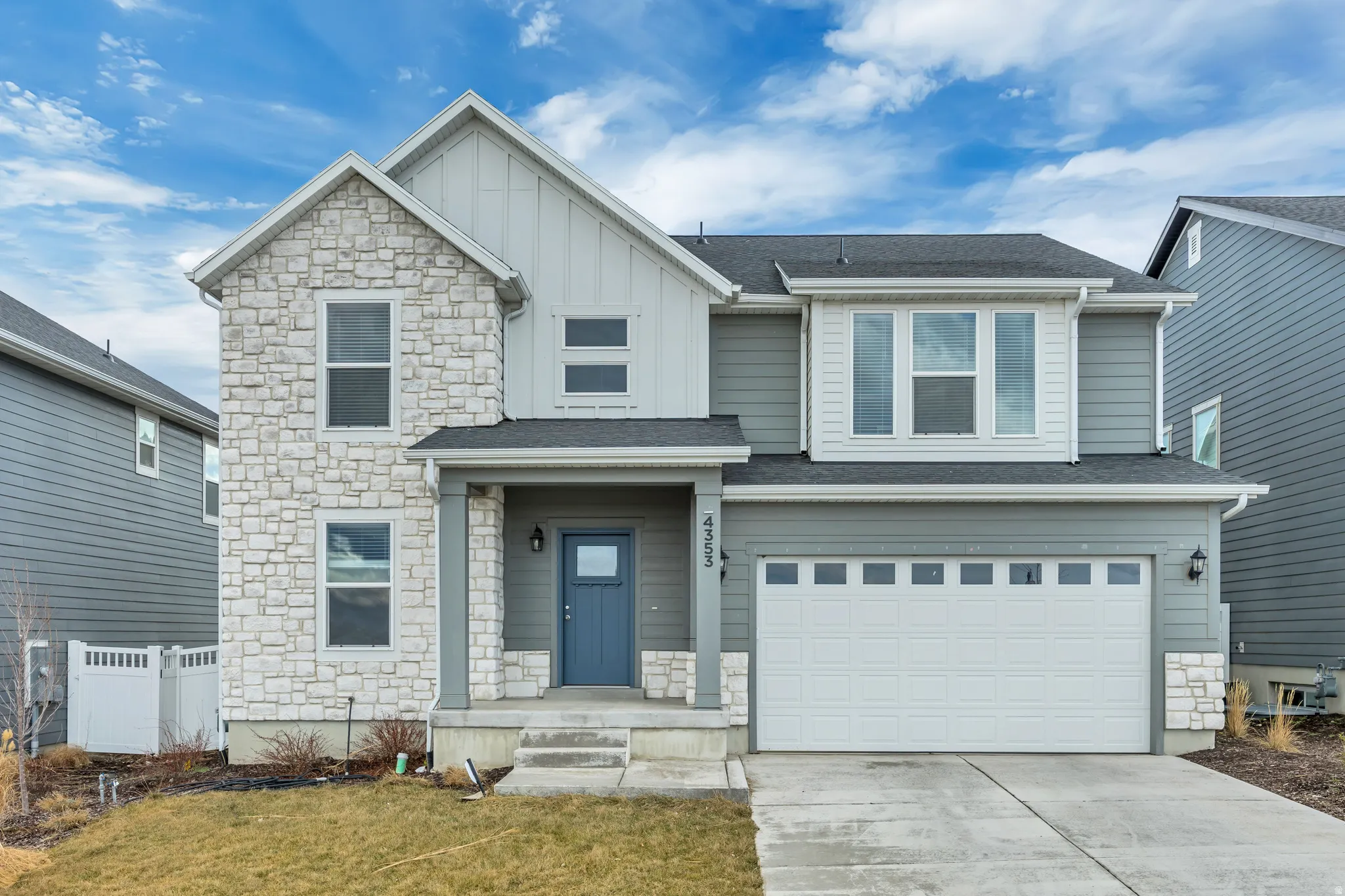 View of front of property with board and batten siding, stone siding, an attached garage, and driveway