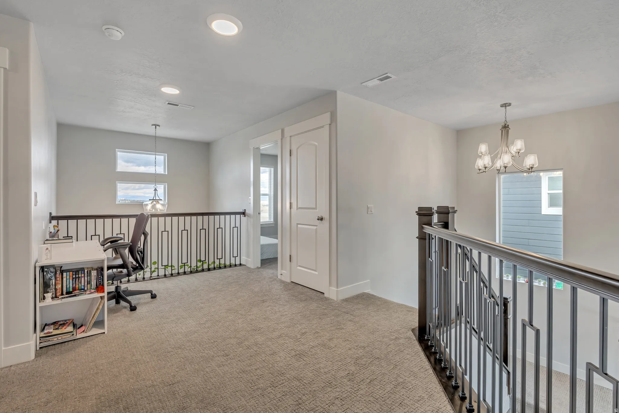 Hallway with a chandelier, an upstairs landing, light carpet, and a textured ceiling