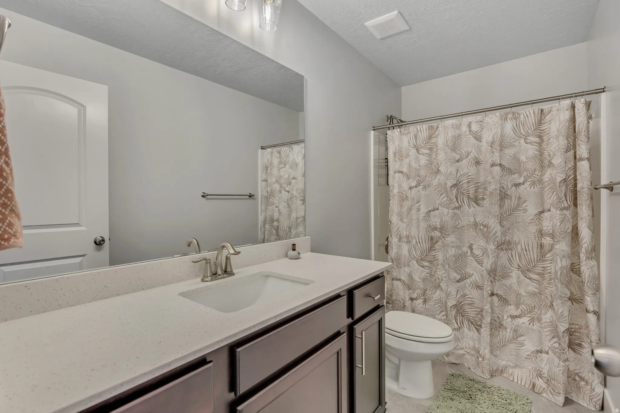 Bathroom with a shower with curtain, vanity, and a textured ceiling