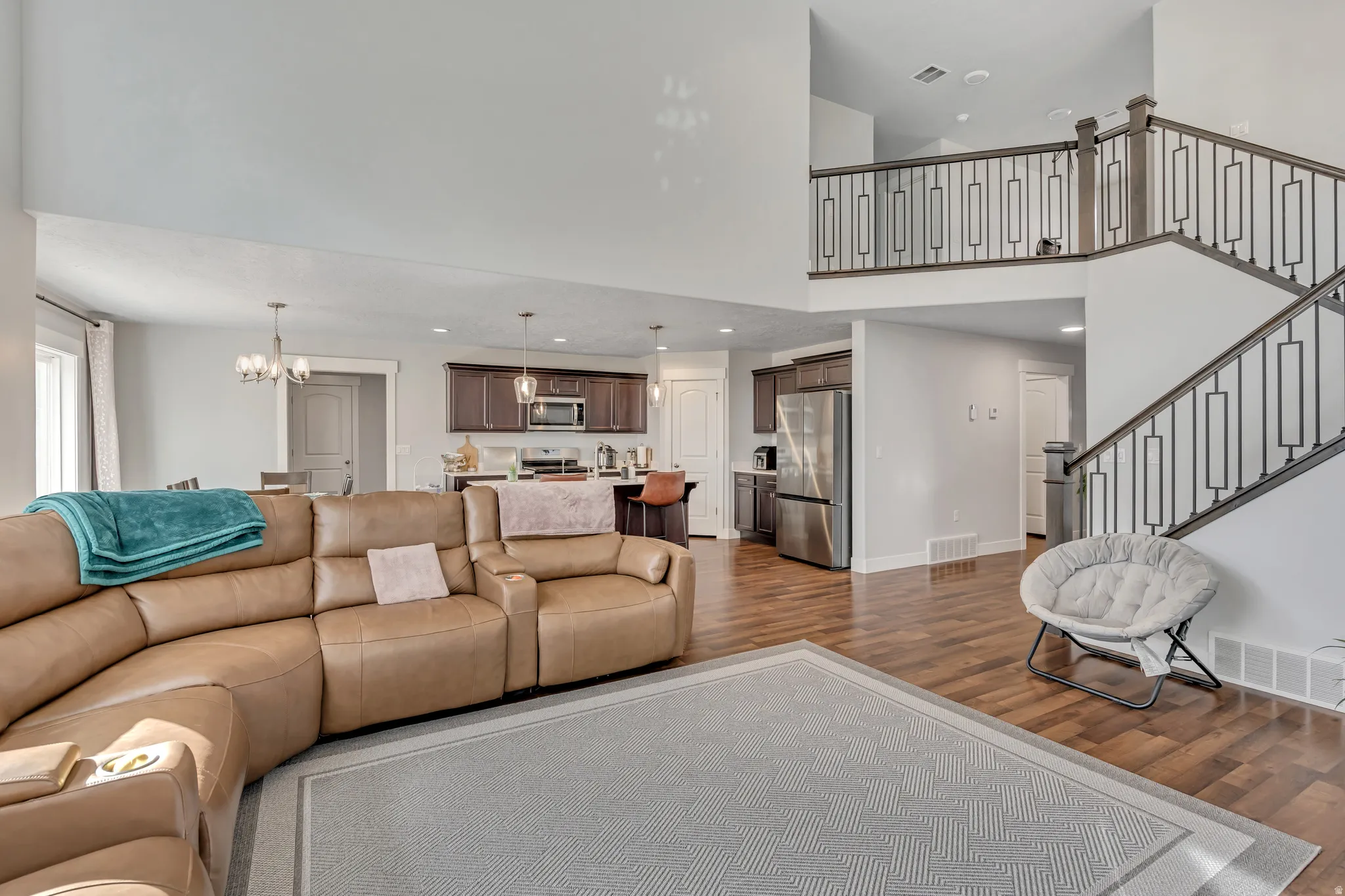 Living room with a high ceiling, dark wood-type flooring, and hanging lights