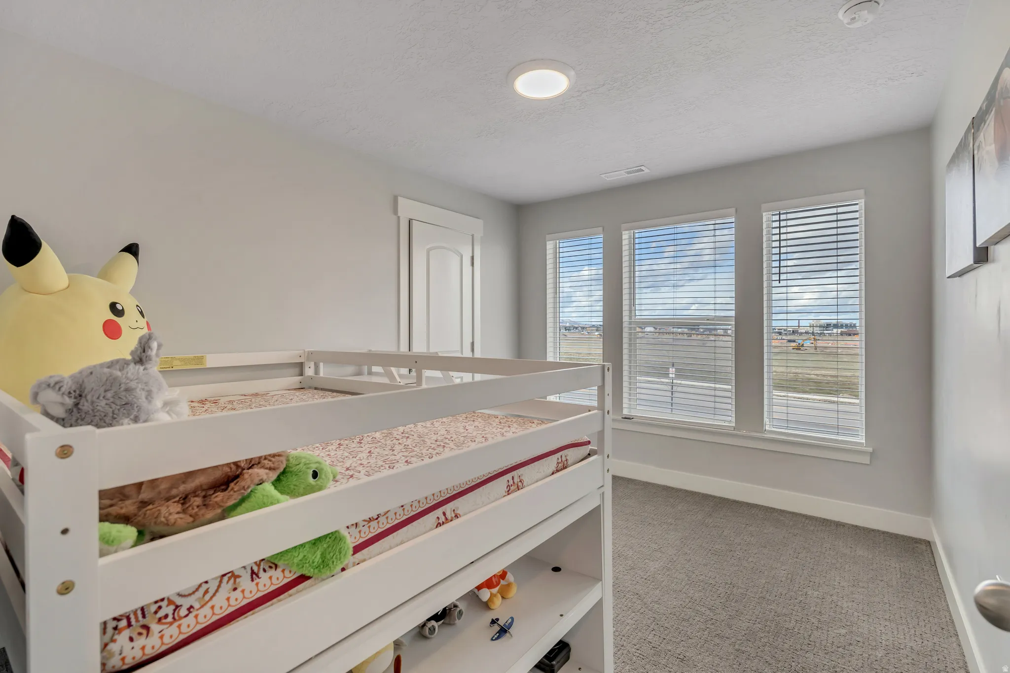 Carpeted bedroom featuring baseboards and a textured ceiling