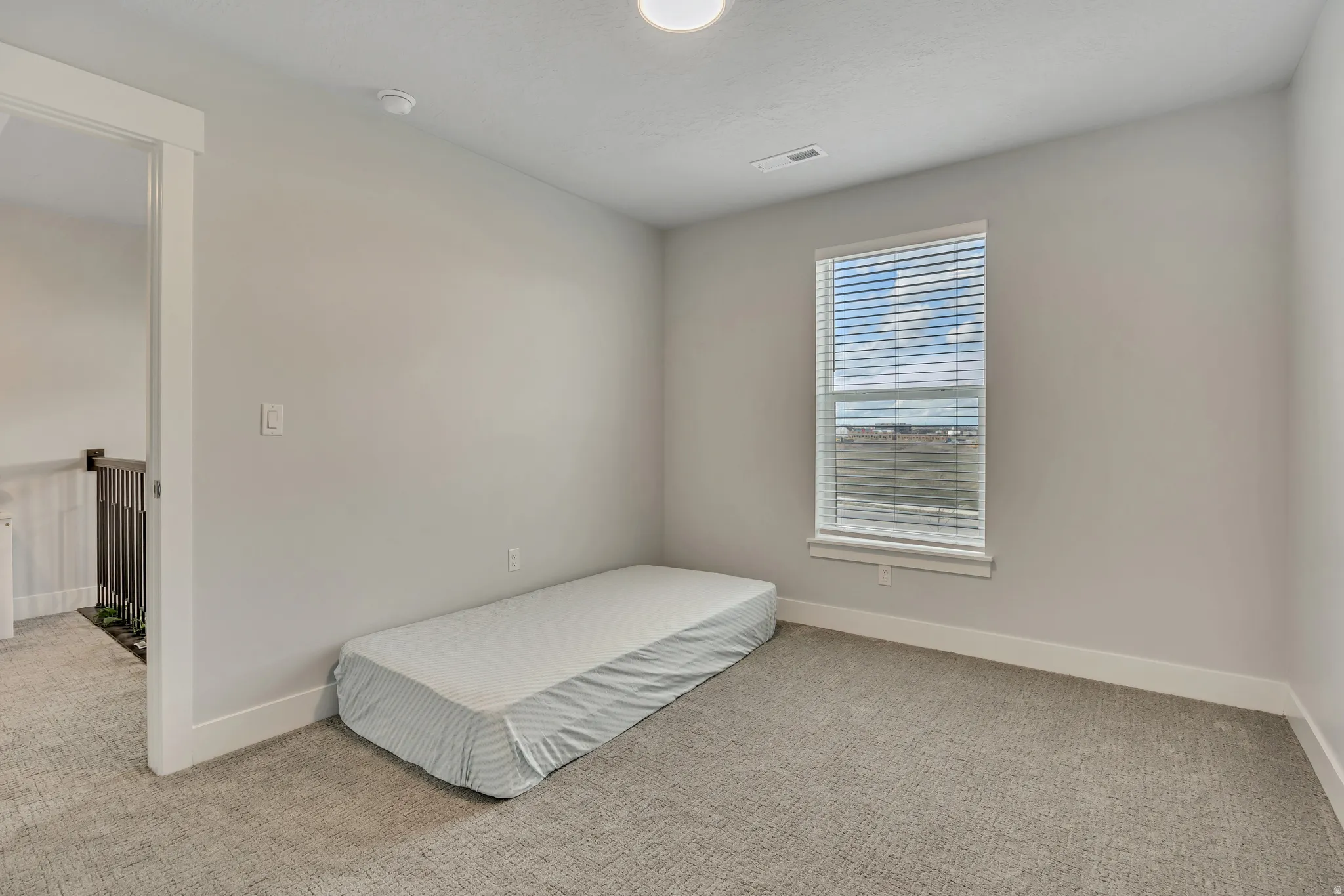Unfurnished bedroom with light carpet and baseboards