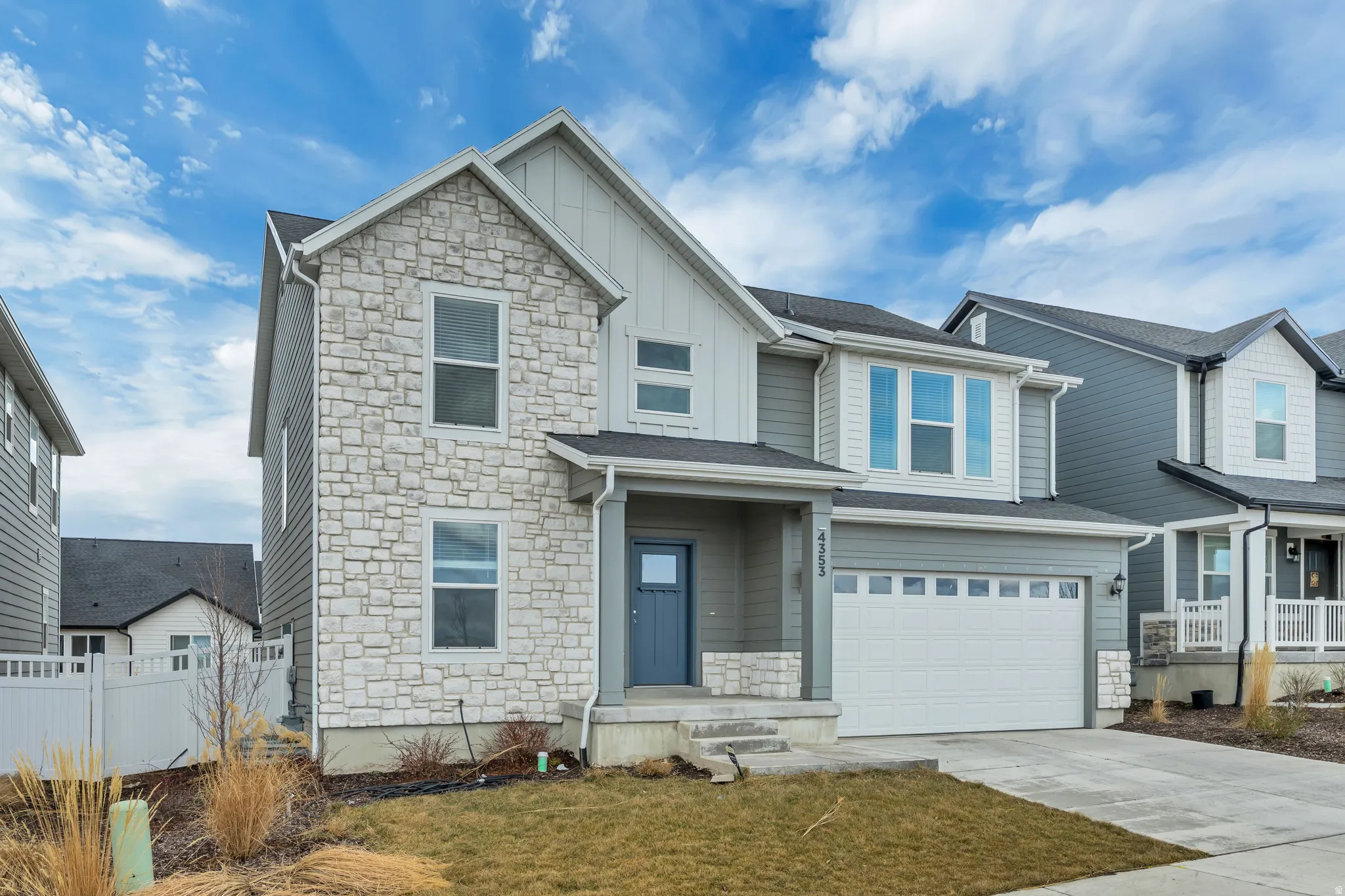 View of front of house featuring stone siding, board and batten siding, an attached garage, and driveway