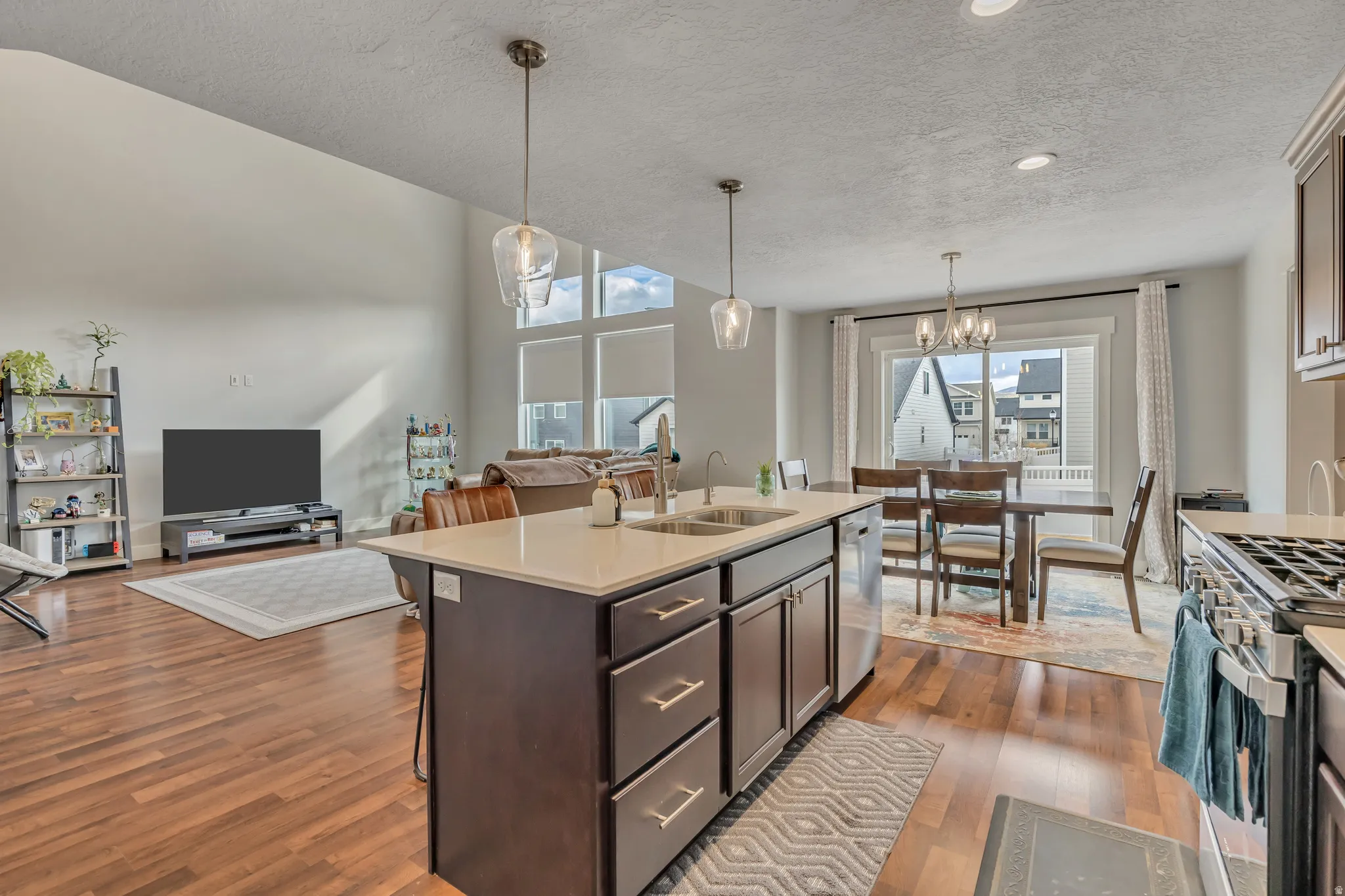 Kitchen featuring open floor plan, stainless steel appliances, dark wood finish cabinetry, a kitchen bar, and light stone countertops