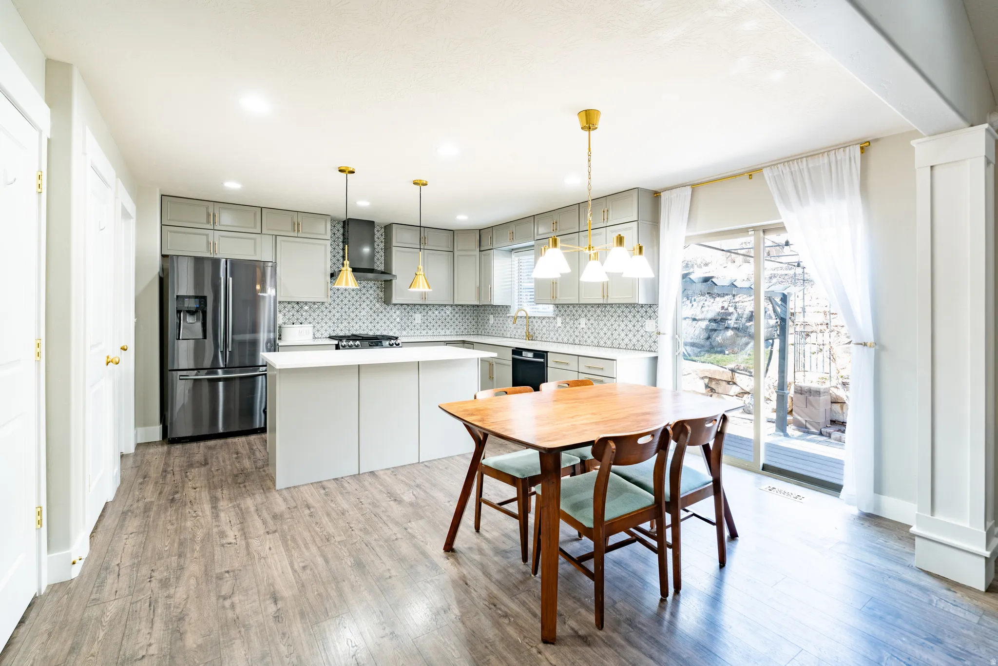 Kitchen featuring light countertops, stainless steel refrigerator with ice dispenser, a kitchen island, gray cabinets, and light wood-style floors