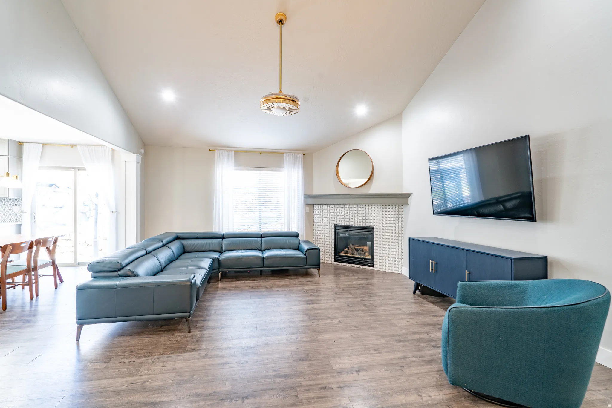 Living area featuring vaulted ceiling, wood finished floors, a fireplace, and recessed lighting