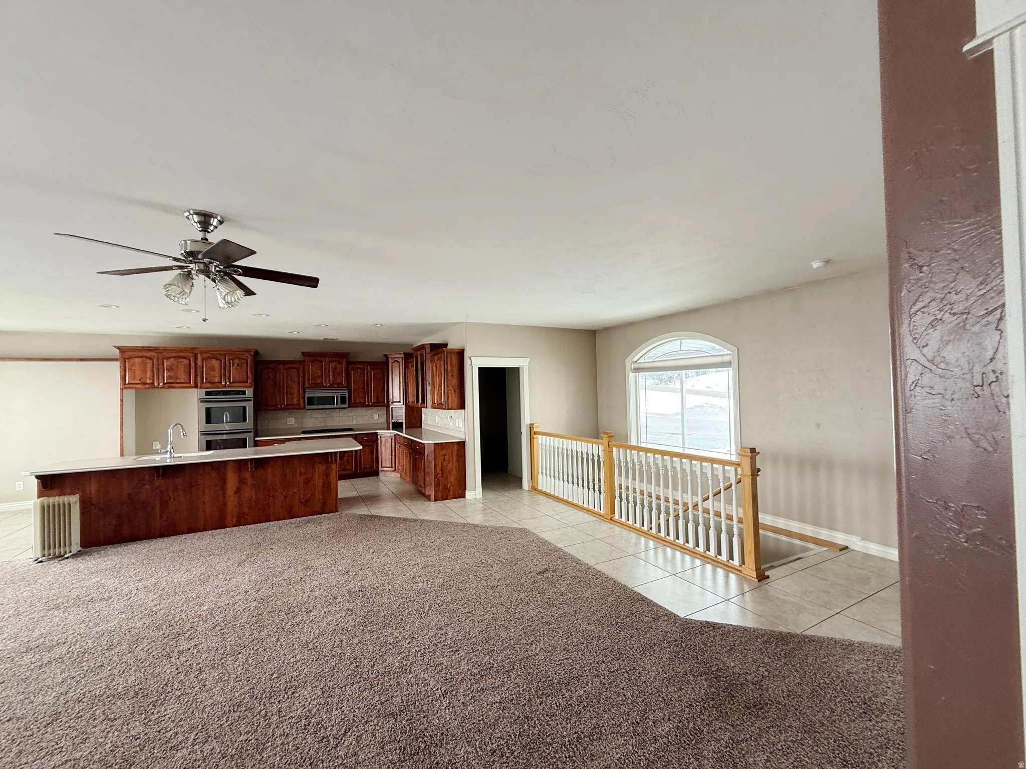 Kitchen featuring light countertops, light tile patterned flooring, a ceiling fan, and light carpet