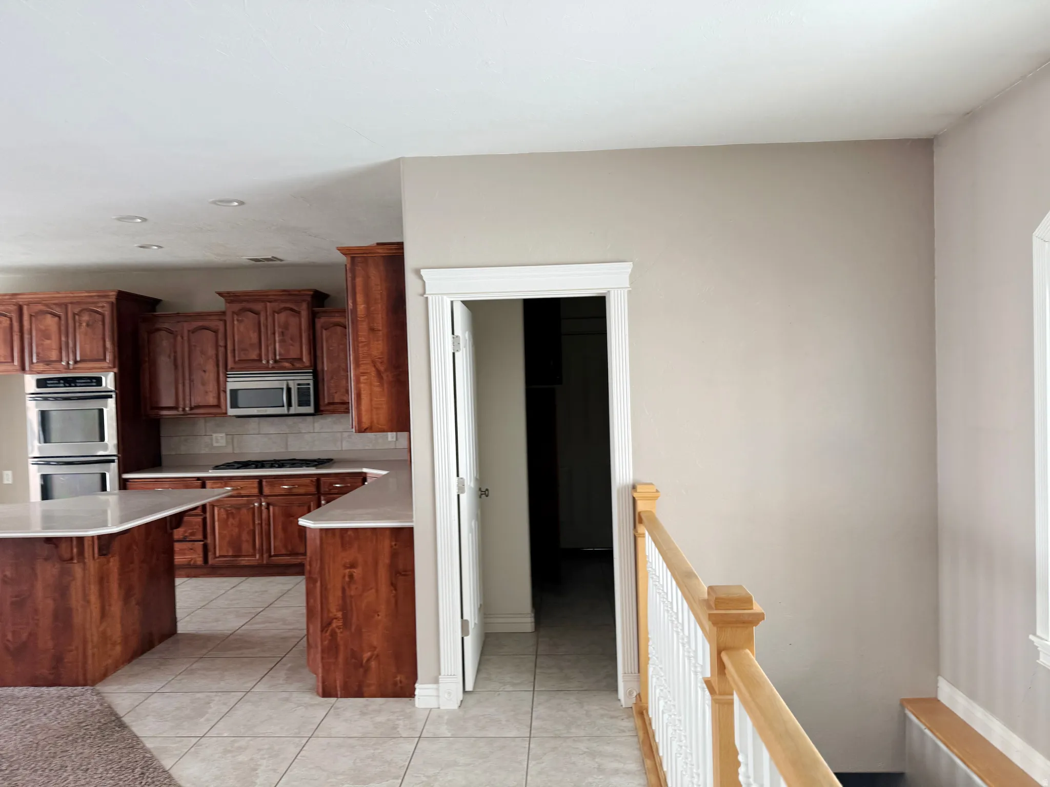Kitchen featuring light countertops, light tile patterned flooring, stainless steel appliances, decorative backsplash, and a breakfast bar