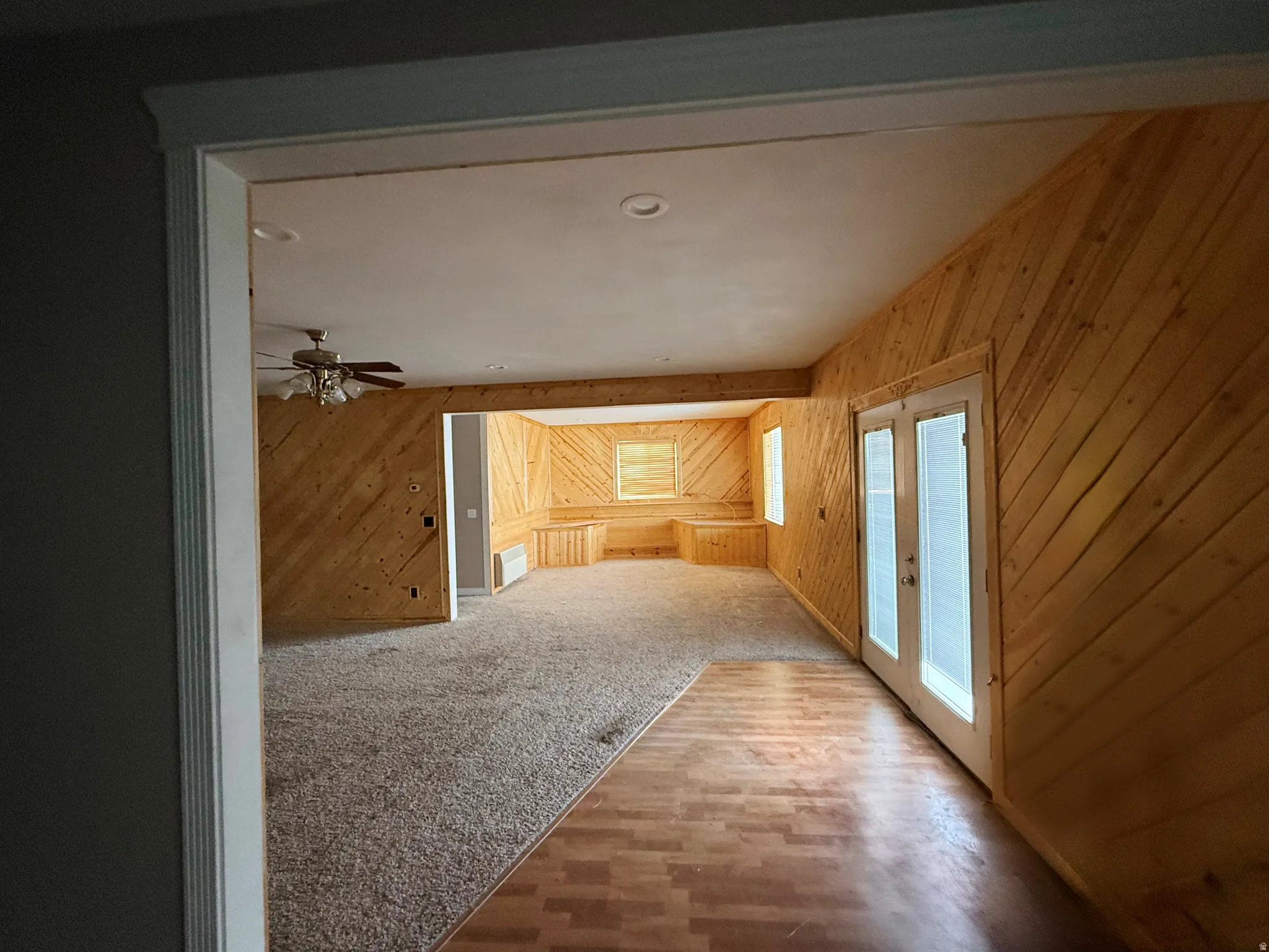 Hall featuring wood walls, recessed lighting, wood finished floors, french doors, and carpet