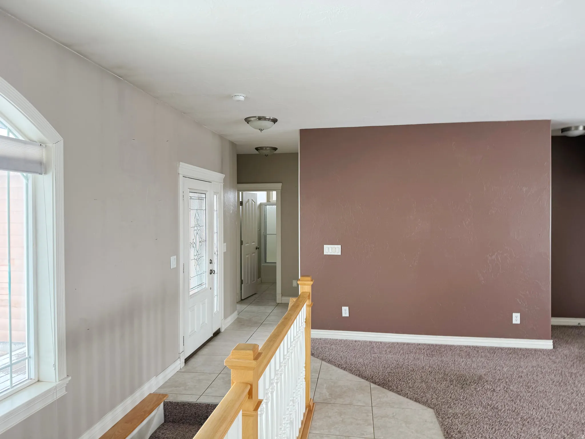 Corridor featuring light tile patterned floors, light colored carpet, and an upstairs landing