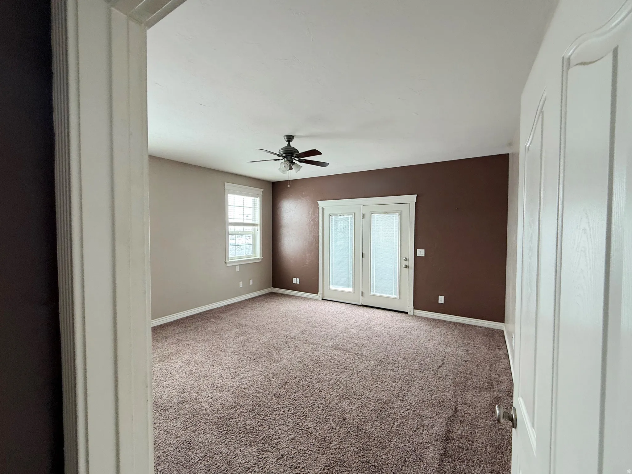 Carpeted spare room featuring baseboards and a ceiling fan