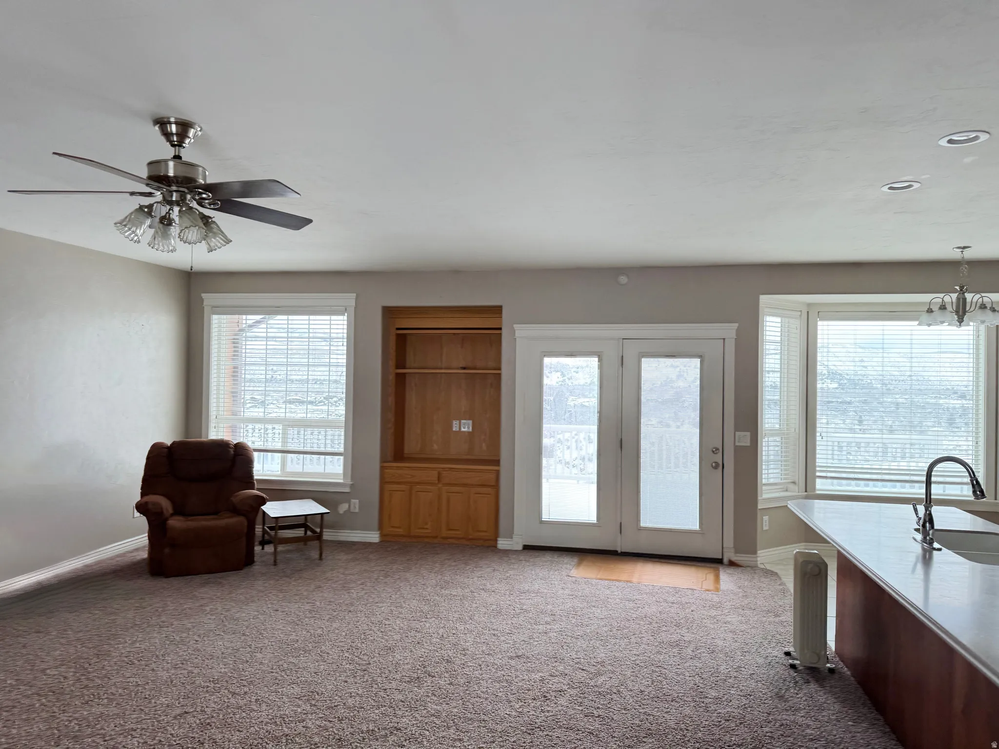 Sitting room with light colored carpet, ceiling fan, and hanging lights