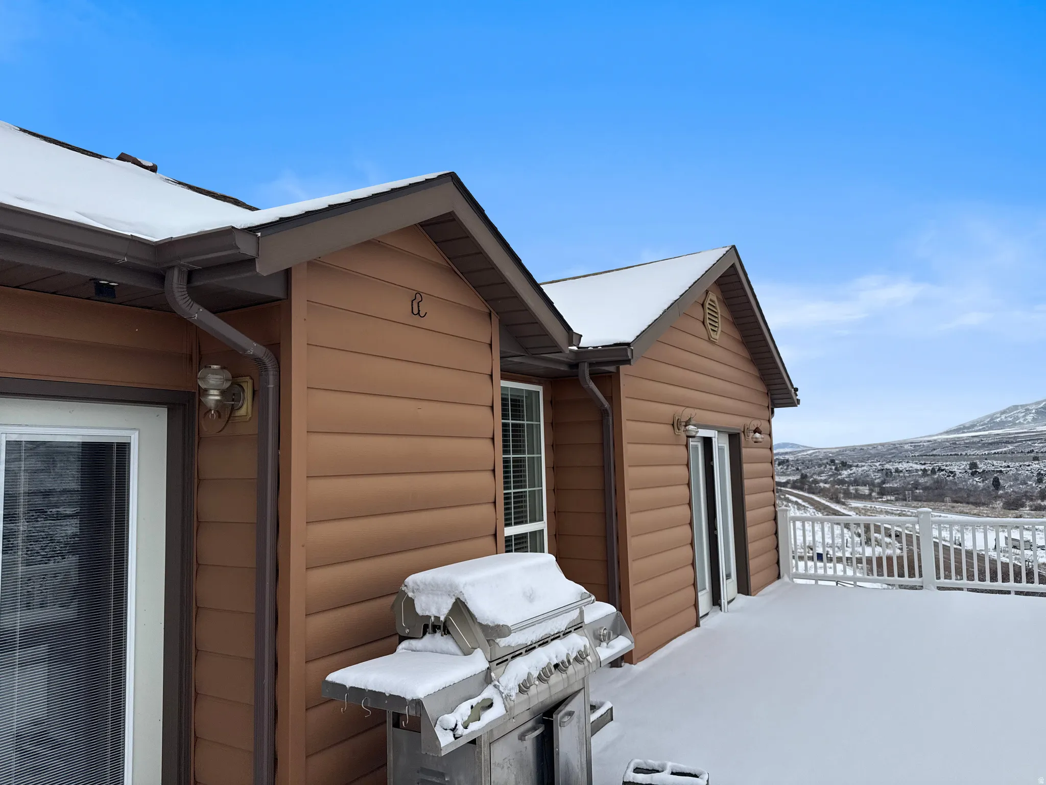 View of snow covered exterior featuring log veneer siding and a deck with mountain view