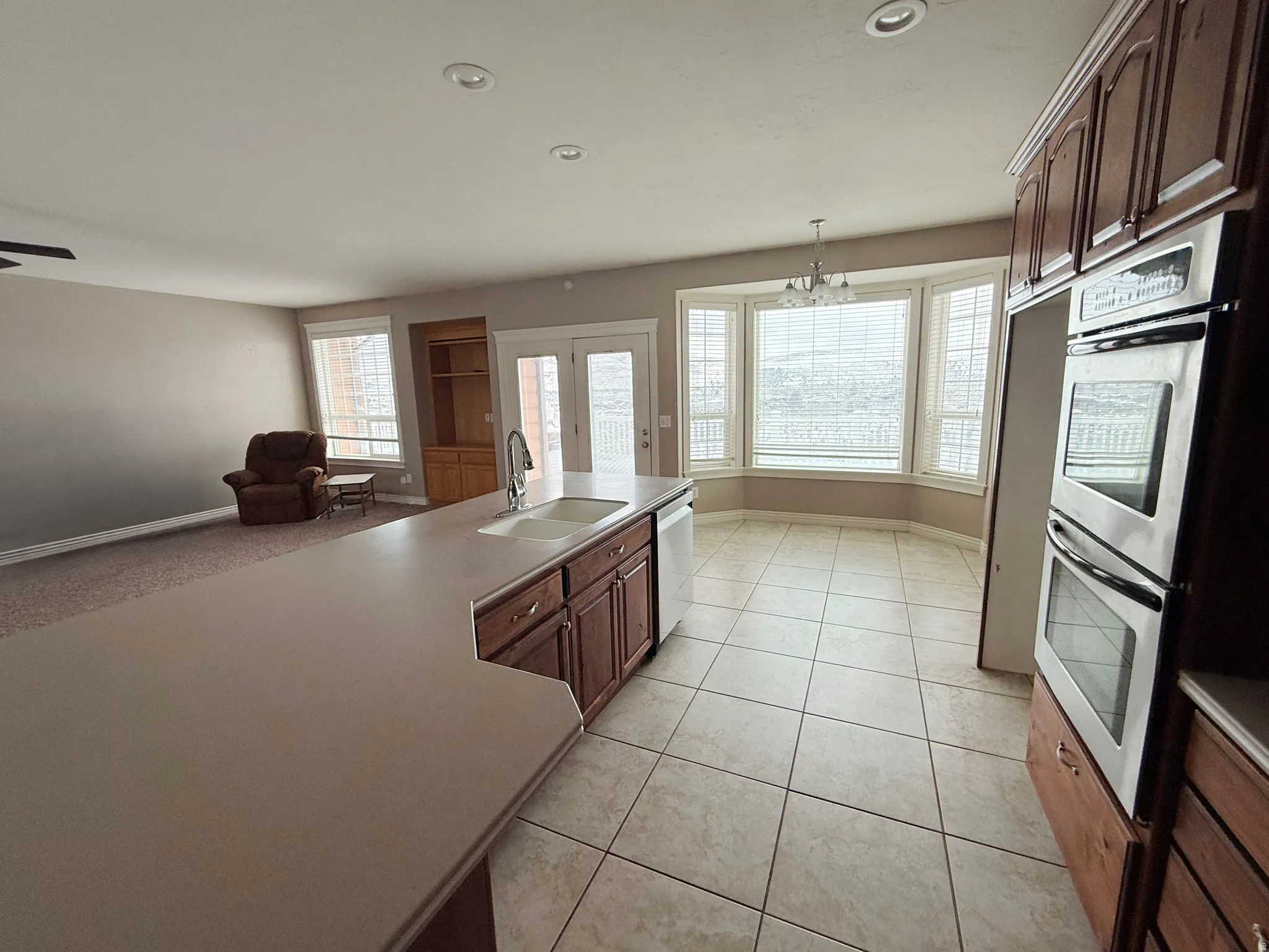 Kitchen with stainless steel appliances, open floor plan, a chandelier, light countertops, and light tile patterned floors