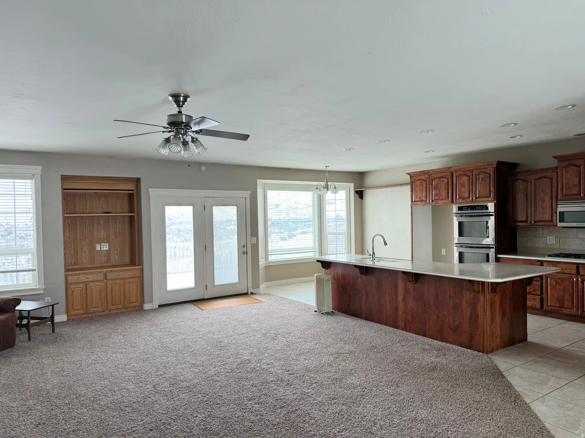 Kitchen with a breakfast bar, stainless steel appliances, a kitchen island with sink, open floor plan, and a chandelier