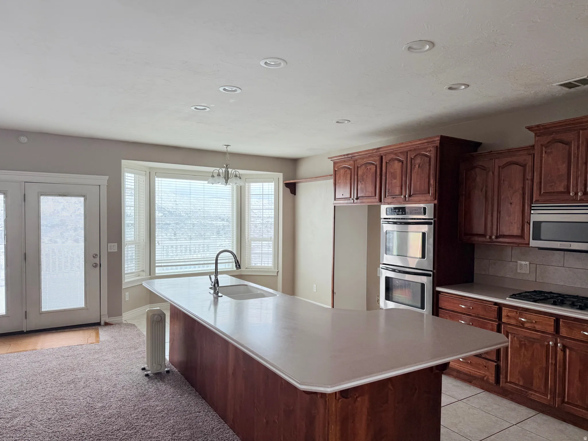 Kitchen with stainless steel appliances, light tile patterned floors, light countertops, a breakfast bar area, and tasteful backsplash