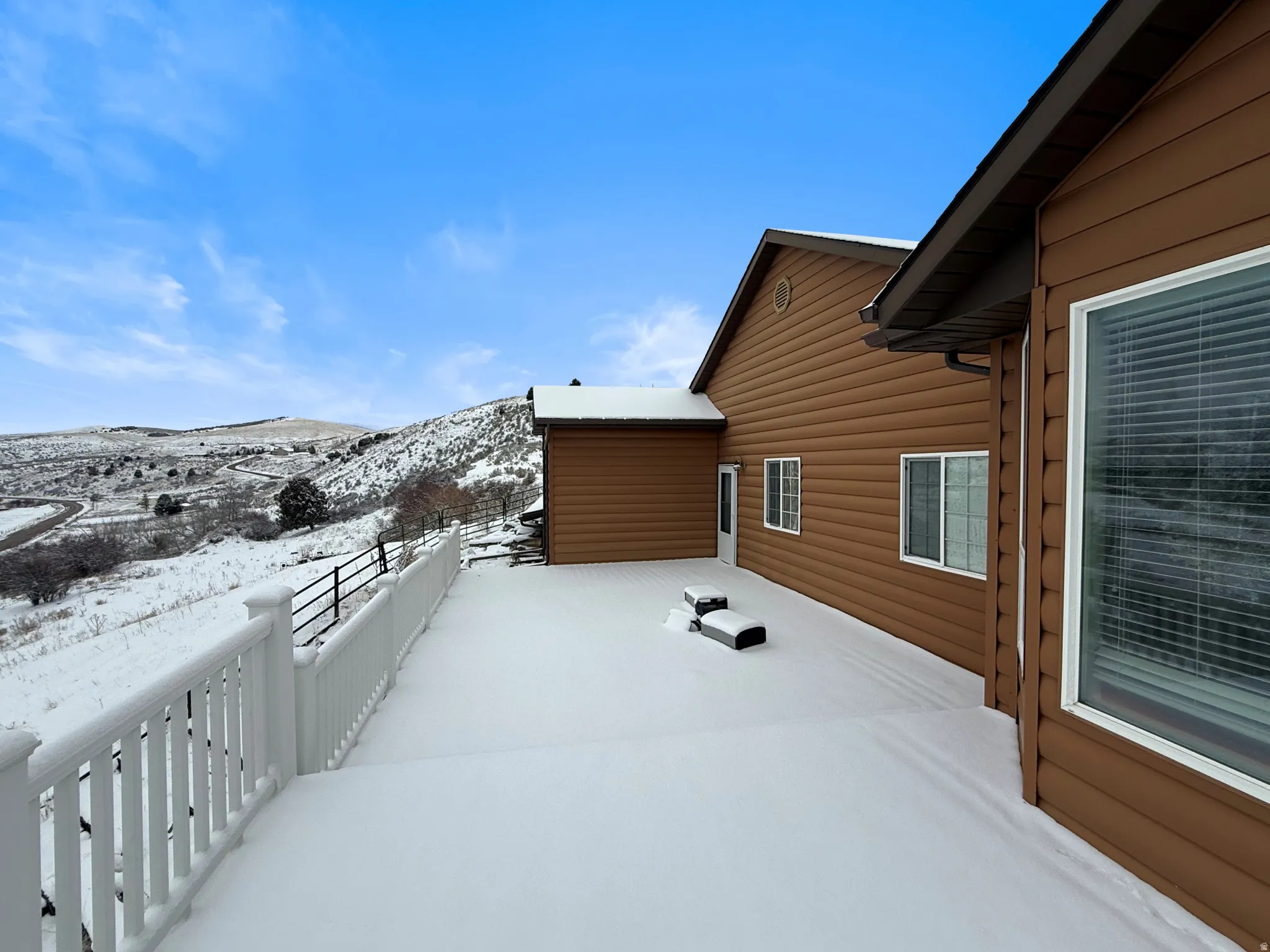 Snow covered patio featuring a wooden deck
