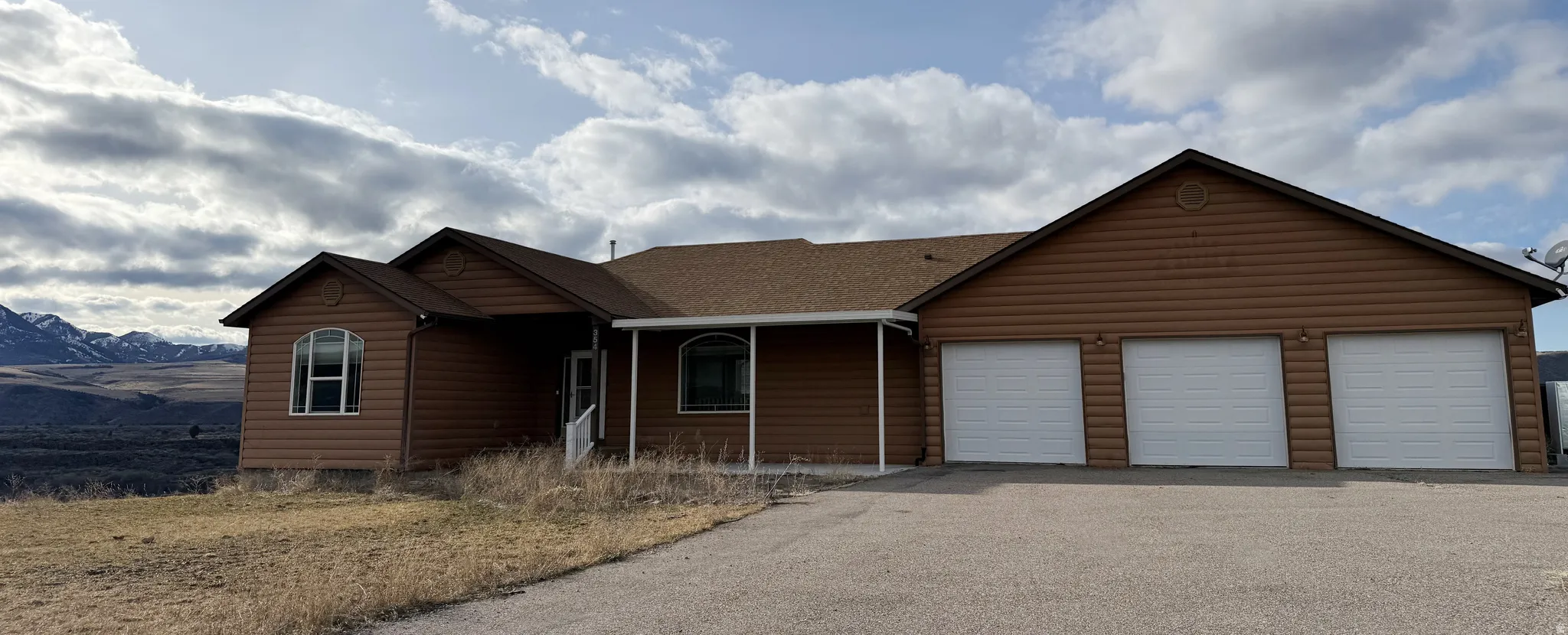 View of front of house with faux log siding, an attached garage, and driveway