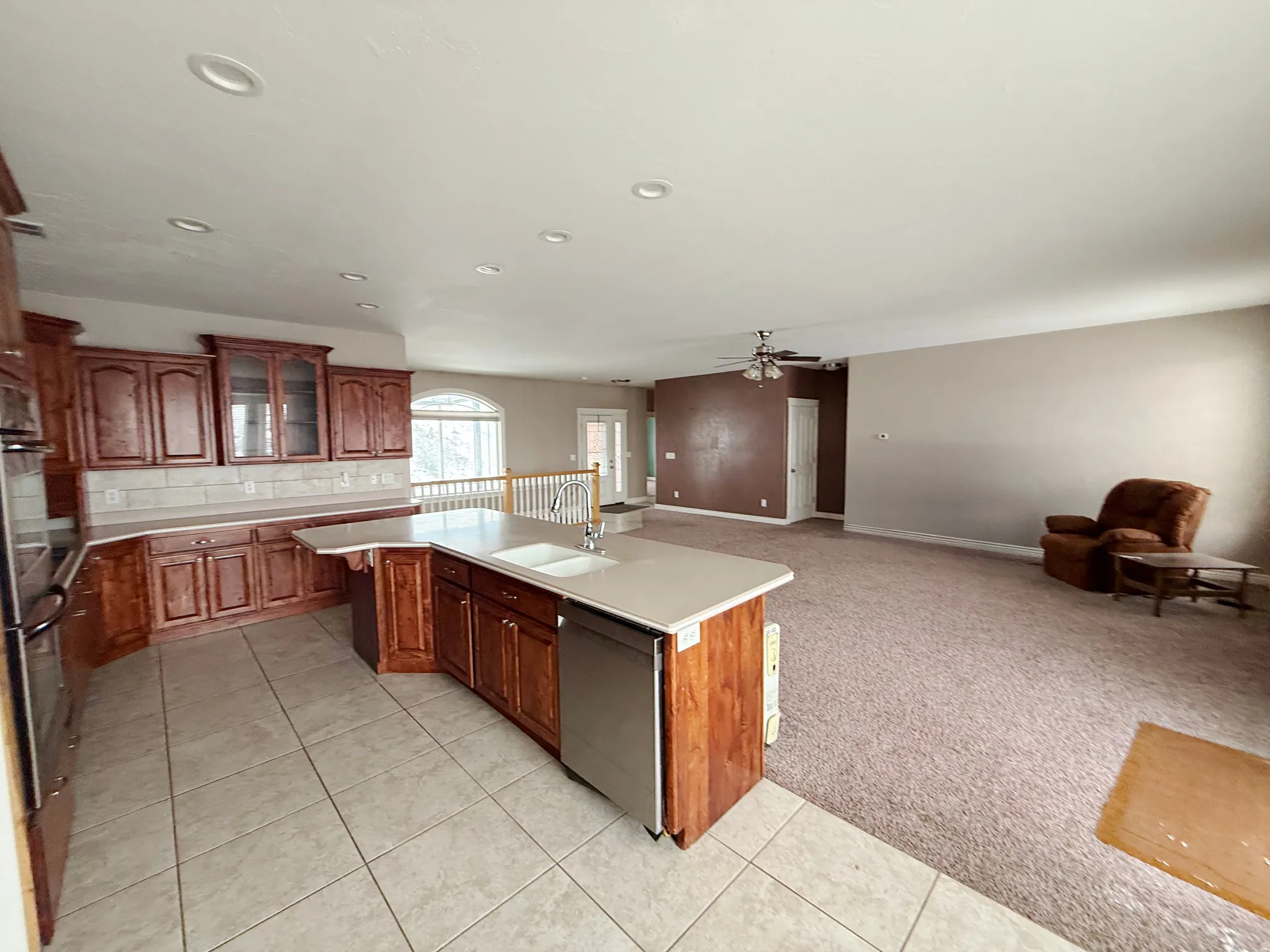 Kitchen with light countertops, light colored carpet, stainless steel appliances, open floor plan, and a center island with sink