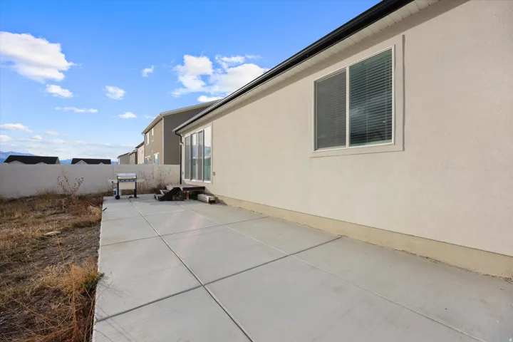 Large concrete slab patio space in backyard.