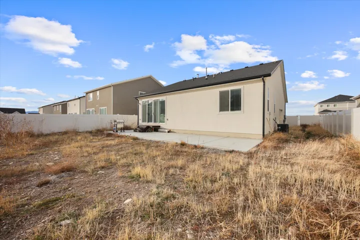 Fully fenced in backyard with large concrete slab patio.